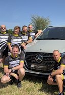 mehrere teilnehmende Mitarbeiter von Schloz Wöllenstein stehen um einen ausgestellten Mercedes-Benz PKW