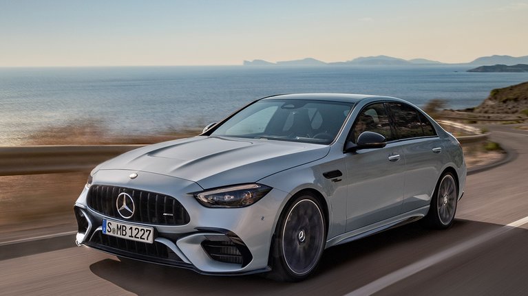 Mercedes-Benz c63 AMG in Silber während der Fahrt, Frontansicht, leicht von der Seite - Im Hintergrund das Meer