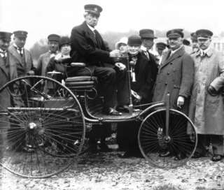 Carl Benz auf seinem ersten Patent-Motorwagen vom Typ I aus dem Jahr 1886. Aufnahme in München im Jahr 1925.