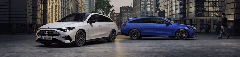 Zwei Mercedes-Benz CLA Shooting Brake, ein weißer und ein blauer, stehen nebeneinander in einer urbanen Straße mit hohen Gebäuden bei Dämmerung.