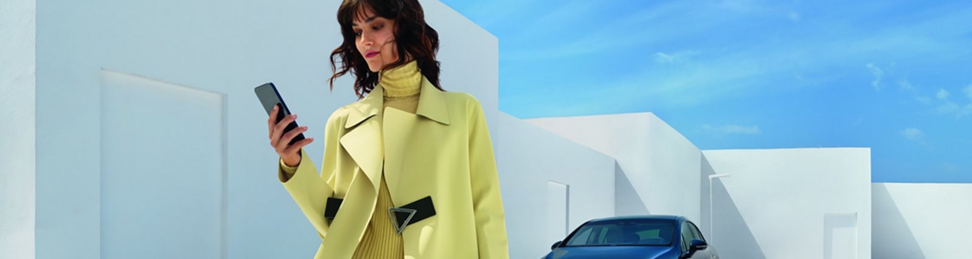Frau mit Smartphone vor Mercedes-Benz PKW
