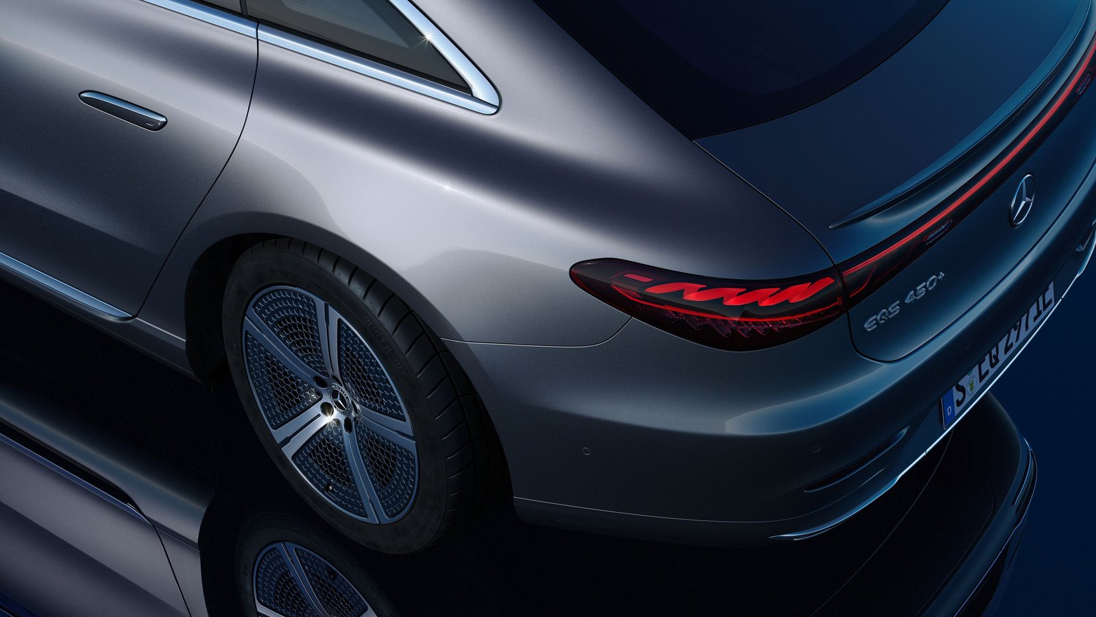 Heckansicht des Mercedes-Benz EQS 450+ mit markanten Rückleuchten und aerodynamischem Design auf dunklem Spiegeluntergrund.