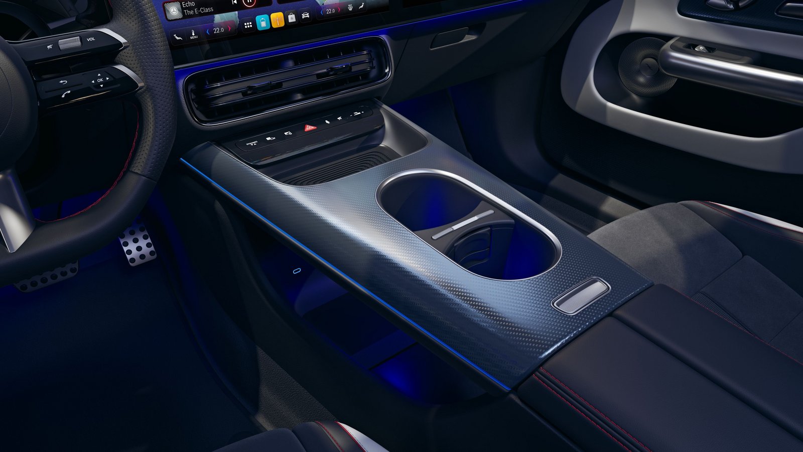 Mittelkonsole eines Mercedes-Benz CLA Shooting Brake mit zwei Getränkehaltern, Carbonfaserstruktur und blauer Ambientebeleuchtung.