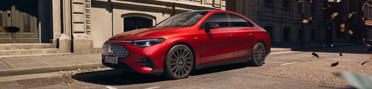 Neuer Mercedes-Benz CLA 250+ in Rot seitlich aufgenommen vor historischer Stadtkulisse mit modernen Designelementen.